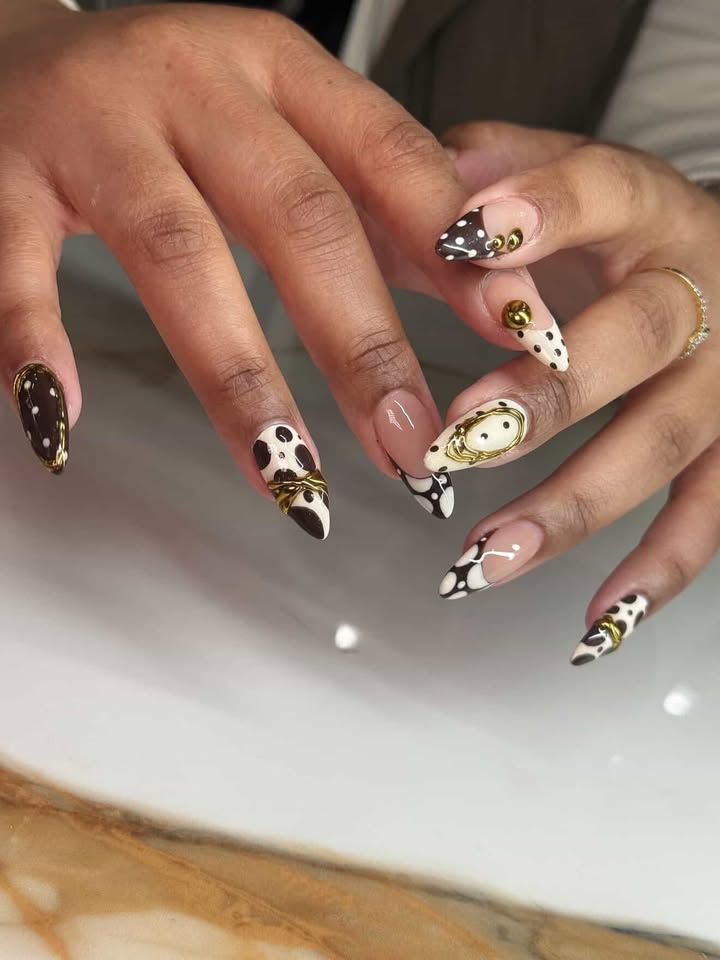 Nude nails with brown cow print French tips and gold charms