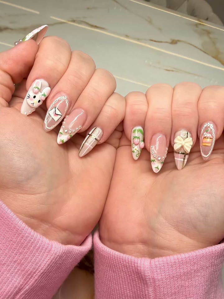 Pink nails with bunny charm, envelope, strawberries, and bow — all on an almond shape