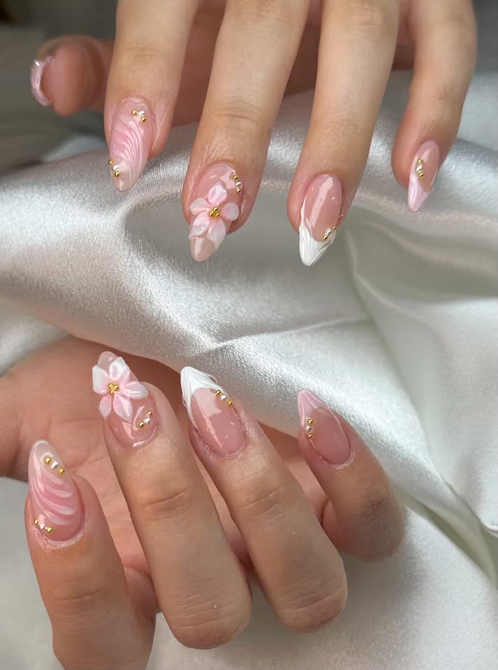 Pink nails with 3D flower sculptures, swirls, and gold beads