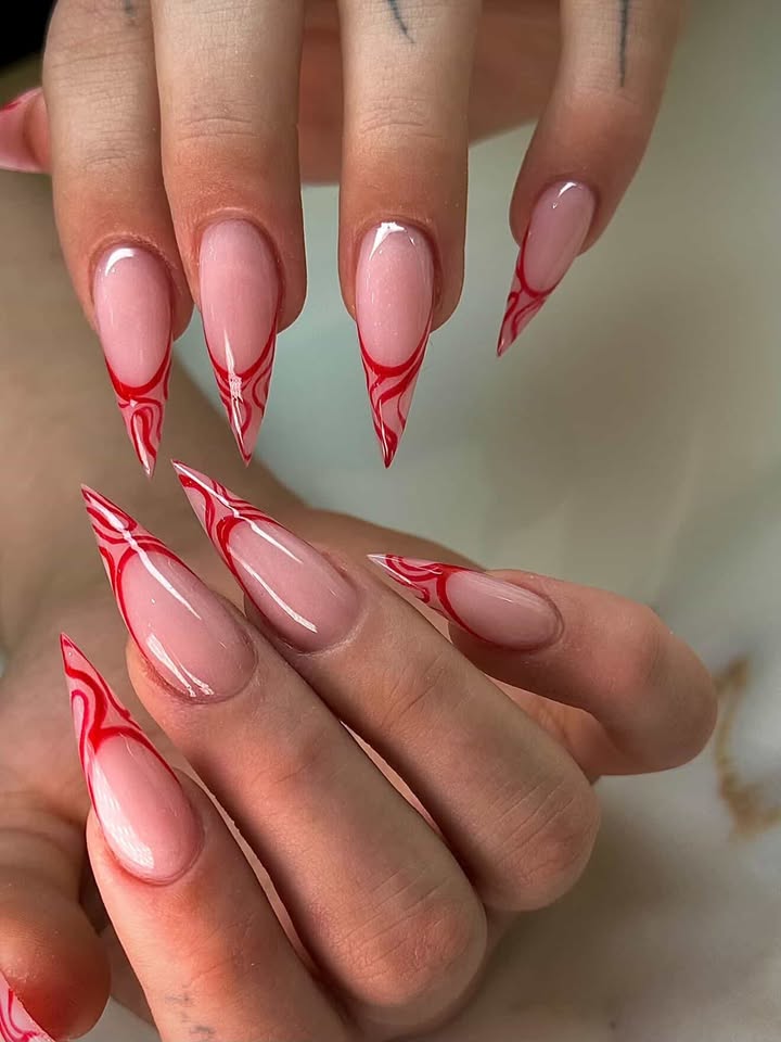 Long stiletto nails with red swirl French tips