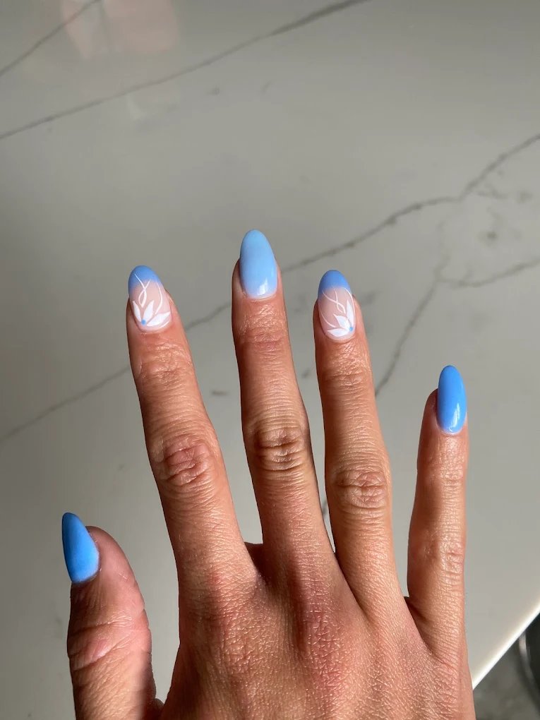 Sky blue nails with white floral line art on accent nails